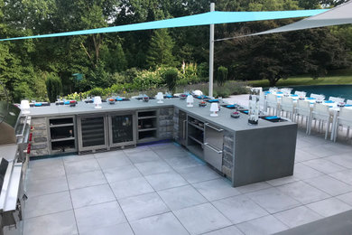 Inspiration for a large contemporary backyard tile patio kitchen remodel in Philadelphia with an awning