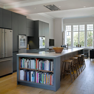 ロンドンの大きいトランジショナルスタイルのおしゃれなキッチン (フラットパネル扉のキャビネット、青いキャビネット、人工大理石カウンター、シルバーの調理設備の、淡色無垢フローリング) の写真