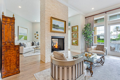 Example of a huge transitional open concept medium tone wood floor and brown floor living room design in Jacksonville with a two-sided fireplace, a stone fireplace and gray walls