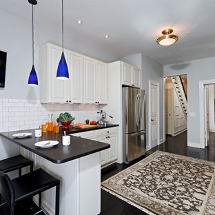 Inspiration for a mid-sized traditional galley kitchen pantry in DC Metro with an undermount sink, raised-panel cabinets, white cabinets, quartz benchtops, white splashback, subway tile splashback, stainless steel appliances, painted wood floors and a peninsula.