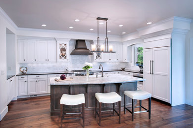 Enclosed kitchen - mid-sized transitional u-shaped dark wood floor and brown floor enclosed kitchen idea in Denver with a farmhouse sink, shaker cabinets, white cabinets, marble countertops, gray backsplash, stone tile backsplash, paneled appliances, an island and gray countertops