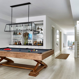 This is an example of an expansive contemporary walk-out basement in New York with white walls, light hardwood flooring and no fireplace.