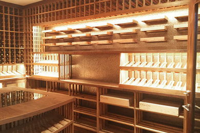Example of a huge trendy light wood floor and brown floor wine cellar design in Los Angeles with display racks