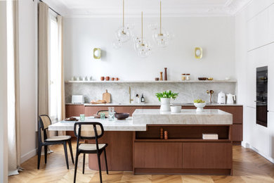 Cette image montre une cuisine parallèle design en bois brun avec un placard à porte plane, une crédence grise, une crédence en dalle de pierre, un sol en bois brun, îlot, un sol marron et un plan de travail gris.