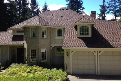 Imagen de fachada de casa beige clásica grande de dos plantas con tejado a cuatro aguas y tejado de teja de madera