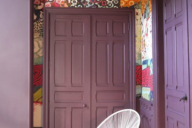 Cette photo montre un très grand hall d'entrée éclectique avec un mur violet, parquet clair, une porte simple, une porte en bois brun et un sol beige.