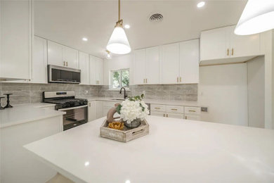 Example of a mid-sized 1960s l-shaped vinyl floor and yellow floor eat-in kitchen design in Dallas with a drop-in sink, shaker cabinets, white cabinets, quartzite countertops, white backsplash, mosaic tile backsplash, stainless steel appliances, an island and white countertops