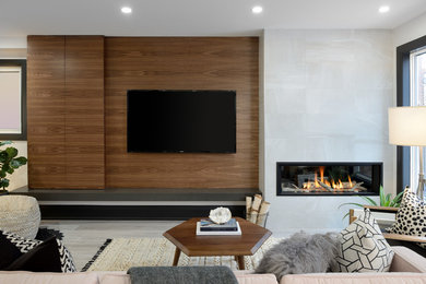 Design ideas for a large modern open concept family room in Toronto with white walls, light hardwood floors, a standard fireplace, a tile fireplace surround and a wall-mounted tv.