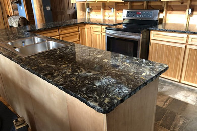 Inspiration for a mid-sized rustic u-shaped light wood floor and beige floor open concept kitchen remodel in Grand Rapids with a double-bowl sink, recessed-panel cabinets, light wood cabinets, quartzite countertops, beige backsplash, wood backsplash, stainless steel appliances, a peninsula and black countertops