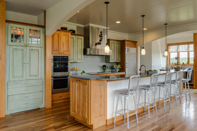 Elegant galley medium tone wood floor kitchen photo in Grand Rapids with raised-panel cabinets, green cabinets, gray backsplash, subway tile backsplash, stainless steel appliances and an island