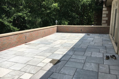 Patio - large contemporary backyard stone patio idea in Other