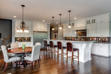 Elegant l-shaped eat-in kitchen photo in Nashville with recessed-panel cabinets, white cabinets, brown backsplash, subway tile backsplash and stainless steel appliances