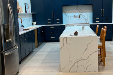 Inspiration for a large modern l-shaped light wood floor and brown floor eat-in kitchen remodel in Newark with a drop-in sink, shaker cabinets, blue cabinets, quartz countertops, white backsplash, quartz backsplash, stainless steel appliances, an island and white countertops