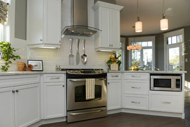 Open concept kitchen - mid-sized transitional dark wood floor and brown floor open concept kitchen idea in Other with an undermount sink, shaker cabinets, white cabinets, white backsplash, ceramic backsplash, stainless steel appliances and a peninsula