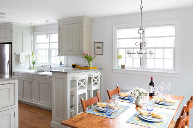Mid-sized transitional u-shaped medium tone wood floor enclosed kitchen photo in New York with an undermount sink, shaker cabinets, beige cabinets, granite countertops, stainless steel appliances and a peninsula