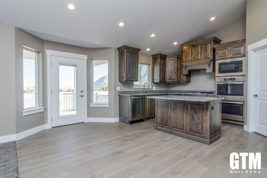 Eat-in kitchen - mid-sized traditional l-shaped light wood floor and gray floor eat-in kitchen idea in Salt Lake City with an undermount sink, recessed-panel cabinets, brown cabinets, granite countertops, stainless steel appliances, an island and gray countertops
