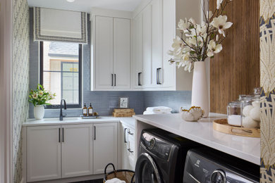 Example of a large transitional l-shaped marble floor, black floor and wallpaper dedicated laundry room design in Denver with white cabinets, quartz countertops, blue backsplash, subway tile backsplash, a side-by-side washer/dryer, white countertops, an undermount sink, recessed-panel cabinets and multicolored walls