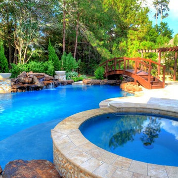 Natural Pool with rock waterfall, bridge, spa, and pergola