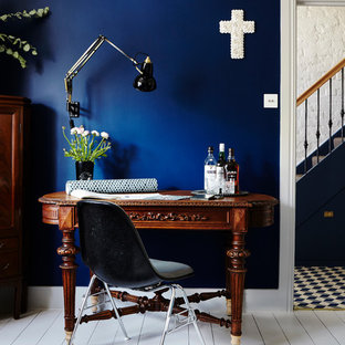 Idéer för ett stort amerikanskt hemmabibliotek, med blå väggar, målat trägolv, en öppen vedspis, en spiselkrans i tegelsten, ett fristående skrivbord och vitt golv