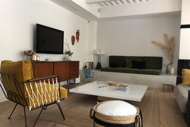 Inspiration pour un grand salon bohème ouvert avec un mur blanc, parquet clair, une cheminée standard, un manteau de cheminée en plâtre, un sol beige et poutres apparentes.