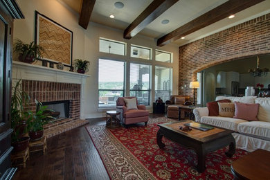 Design ideas for a traditional family room in Austin with white walls, dark hardwood floors, a standard fireplace, a brick fireplace surround and brown floor.