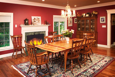 Enclosed dining room - medium tone wood floor enclosed dining room idea in New York with red walls, a standard fireplace and a tile fireplace