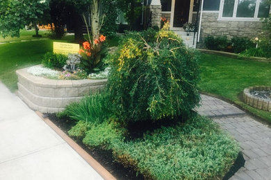 This is an example of a small craftsman full sun front yard concrete paver landscaping in Calgary for summer.
