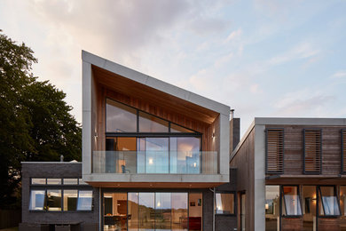 Inspiration for a contemporary two-storey brown house exterior in Hertfordshire with wood siding and a gable roof.