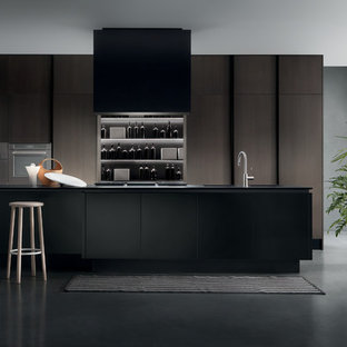 Einzeilige, Große Moderne Küche mit Vorratsschrank, integriertem Waschbecken, flächenbündigen Schrankfronten, schwarzen Schränken, Quarzwerkstein-Arbeitsplatte, Elektrogeräten mit Frontblende, Betonboden, Kücheninsel, Küchenrückwand in Grau, Rückwand aus Stein und grauem Boden in Toronto