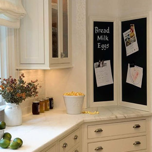 Transitional kitchen pantry ideas - Inspiration for a transitional u-shaped ceramic floor kitchen pantry remodel in Newark with a farmhouse sink, recessed-panel cabinets, white cabinets, marble countertops, white backsplash, ceramic backsplash, paneled appliances and an island