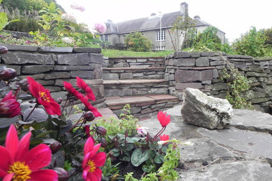 Design ideas for a large rural back garden for summer in Other with a retaining wall and natural stone paving.