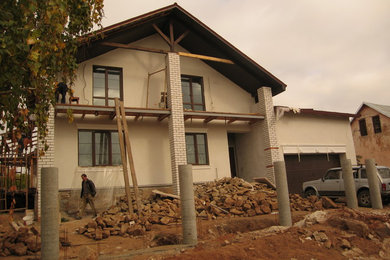 Modelo de fachada de casa beige contemporánea de tamaño medio de dos plantas con revestimientos combinados, tejado a dos aguas y tejado de teja de madera