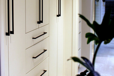 Example of a small trendy carpeted and beige floor built-in closet design in Toronto with flat-panel cabinets and white cabinets