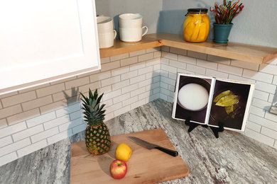 Mid-sized minimalist u-shaped porcelain tile and gray floor eat-in kitchen photo in Austin with an undermount sink, shaker cabinets, white cabinets, granite countertops, white backsplash, subway tile backsplash, black appliances and gray countertops