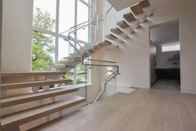 Foto de escalera suspendida moderna con escalones de madera y barandilla de vidrio