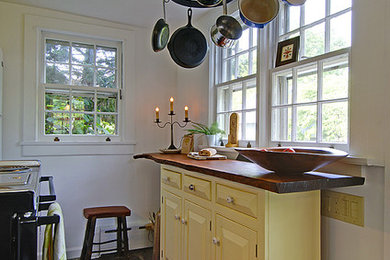 Enclosed kitchen - small eclectic u-shaped slate floor enclosed kitchen idea in Philadelphia with a farmhouse sink, raised-panel cabinets, yellow cabinets, wood countertops, white backsplash, white appliances and no island