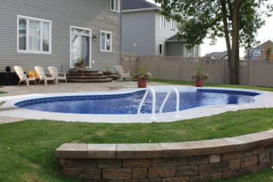 Ejemplo de piscina de tamaño medio en patio trasero con suelo de hormigón estampado