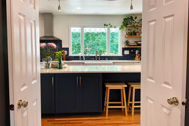 Inspiration for a large transitional u-shaped open plan kitchen in DC Metro with a farmhouse sink, shaker cabinets, blue cabinets, quartz benchtops, blue splashback, porcelain splashback, stainless steel appliances, light hardwood floors, with island, beige floor and white benchtop.