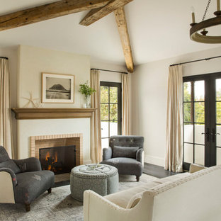 Imagen de salón mediterráneo con paredes beige, suelo de madera oscura, chimenea tradicional, marco de chimenea de ladrillo y suelo marrón