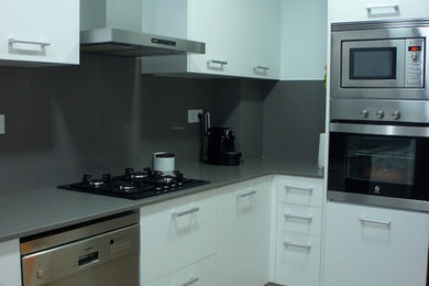 Modelo de cocina moderna de tamaño medio con fregadero bajoencimera, electrodomésticos de acero inoxidable y suelo de baldosas de porcelana