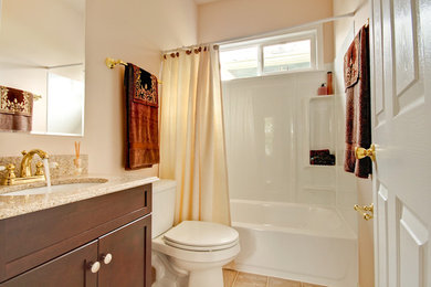 Photo of a mid-sized traditional bathroom in Seattle with shaker cabinets, dark wood cabinets, an alcove tub, a shower/bathtub combo, a two-piece toilet, white tile, orange walls, porcelain floors, an undermount sink, engineered quartz benchtops and a shower curtain.
