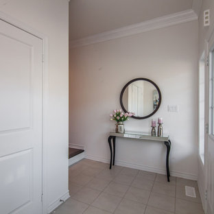 Eklektisk inredning av en mellanstor foajé, med vita väggar, klinkergolv i porslin, en dubbeldörr, en vit dörr och vitt golv