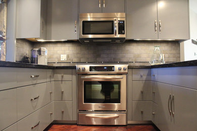 Kitchen - large transitional u-shaped medium tone wood floor and brown floor kitchen idea in Phoenix with flat-panel cabinets, gray cabinets, gray backsplash, subway tile backsplash, stainless steel appliances and a peninsula