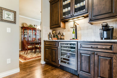 Inspiration for a small rustic single-wall medium tone wood floor wet bar remodel in Denver with raised-panel cabinets, dark wood cabinets, marble countertops and beige backsplash