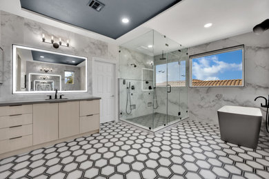 Large master gray tile and marble tile mosaic tile floor and double-sink bathroom photo in Las Vegas with flat-panel cabinets, beige cabinets, a one-piece toilet, gray walls, an undermount sink, quartzite countertops, a hinged shower door, gray countertops and a freestanding vanity