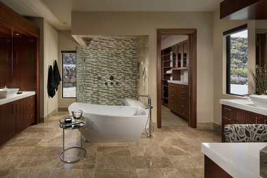 This is an example of a bathroom in Las Vegas with flat-panel cabinets, dark wood cabinets, a freestanding tub, beige walls, a vessel sink, brown floor, a hinged shower door and white benchtops.