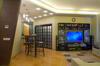 Réalisation d'un grand salon asiatique ouvert avec un mur vert, parquet clair et un téléviseur encastré.