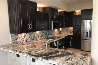 Eat-in kitchen - large transitional eat-in kitchen idea in Chicago with raised-panel cabinets, dark wood cabinets, granite countertops and a peninsula