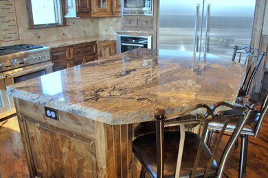 Example of a huge mountain style medium tone wood floor eat-in kitchen design in Kansas City with a farmhouse sink, raised-panel cabinets, medium tone wood cabinets, granite countertops, beige backsplash, stone tile backsplash, stainless steel appliances and an island