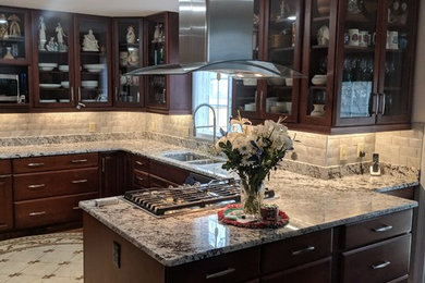 Inspiration for a kitchen remodel in New York with a double-bowl sink, glass-front cabinets, dark wood cabinets, granite countertops, white backsplash, glass tile backsplash, stainless steel appliances and white countertops
